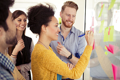 Happy young students working together on a whiteboard