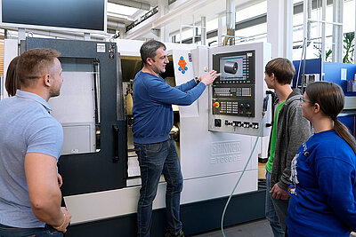 Dozent mit Studierenden in der Maschinenhalle