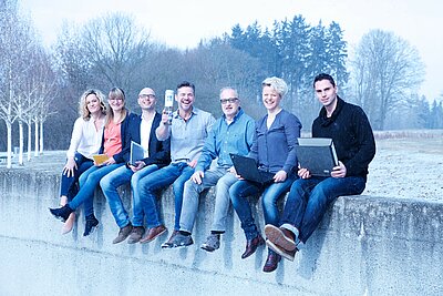 Team des Studienbüros sitzend auf einer Mauer