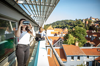 Studierende mit VR-Brille auf Balkon