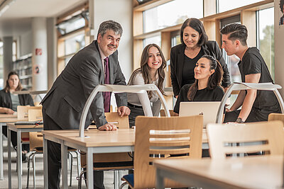 Studierende und Professoren an Tisch in Bibliothek