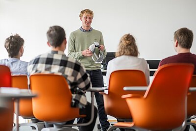 Vorlesungssituation mit einem Professor und vier Studierenden