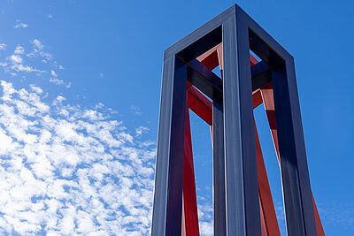 Rot-blaue Stele am Alfons-Goppel-Platz vor blauem Himmel