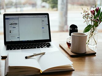 Laptop, Buch und Tasse
